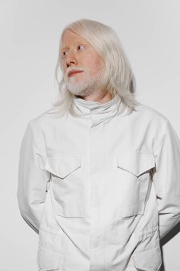 Moda, manken, beyaz önlüklü uzun beyaz saçlı ve sakallı bir adamın portresi, sade beyaz bir arka planda, minimalist bir tarz ve yansıtıcı bir hava sergiliyor, sanatsal projeler için mükemmel.