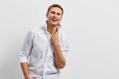 Beyaz gömlekli, kolları kıvrılmış, gri arka planda neşeli görünen mutlu bir adam. Kendinden emin ve rahat ifade, günlük kıyafetler, orta yaşlı erkek model, pozitif enerji, stüdyo