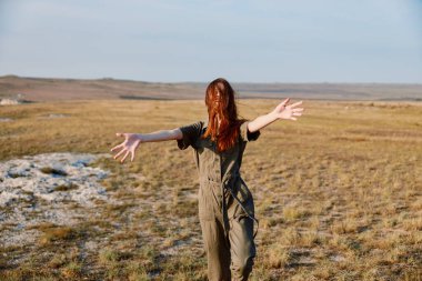 Sahada özgürlük, doğayı kucaklayan, açık alan ve kollarını açarak zarif pozlar veren ifade gücü yüksek bir kadın.