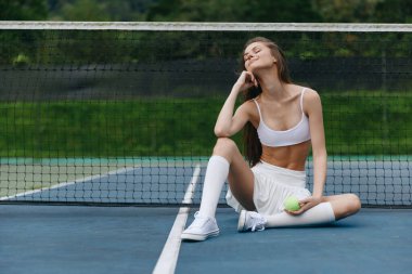 Tenis kortunda oturan rahat spor model, mutluluk ve güven yayıyor, fitness, spor ve sağlıklı yaşam tarzı temaları için mükemmel.