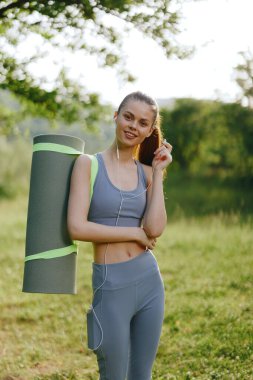 Doğal ortamında yoga minderi olan, kendine güveni ve sağlık bilinci olan, yaz aylarında sağlık ve zindelik kavramları için mükemmel bir kadın.