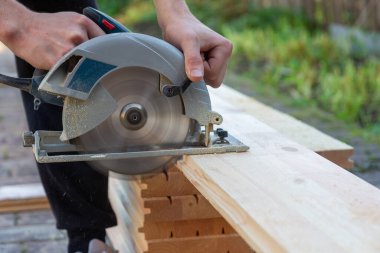 a carpenter cuts wooden floorboards with a circular saw