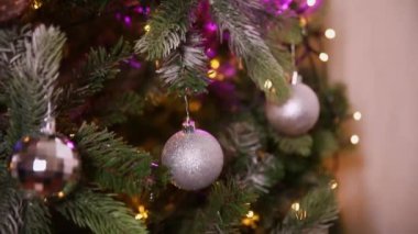 Klasik yeni yıl ağacı, gümüş, beyaz, pembe süsleme oyuncakları, top ve çözünmüş çelenk ışıklarıyla süslenmiş. Modern klasik tatil tasarımı. Evde Noel arifesi