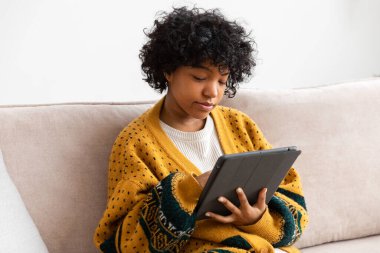 African american girl holding digital tablet touch screen typing scroll page at home. Woman with mobile tech device surfing internet using social media apps playing game. Study work shopping online