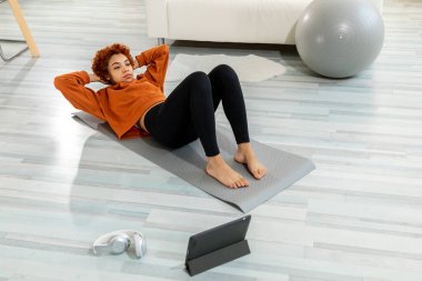 Fitness Workout training. Young healthy fit african girl doing bicycle crunch abs exercise on yoga mat on floor at home. Athletic woman in sportswear is pumping abdominals. Sport and fitness