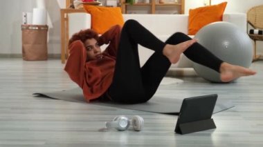 Fitness Workout training. Young healthy fit african girl doing bicycle crunch abs exercise on yoga mat on floor at home. Athletic woman in sportswear is pumping abdominals. Sport and fitness
