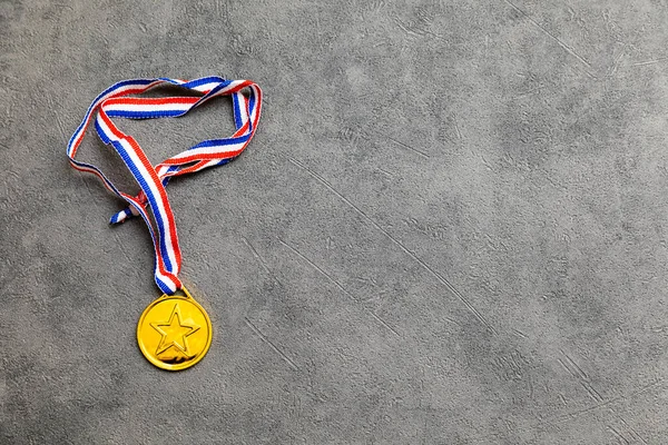 Simply flat lay design winner or champion gold trophy medal on concrete stone grey background. Victory first place of competition. Winning or success concept. Top view flat lay copy space