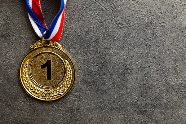 Simply flat lay design winner or champion gold trophy medal on concrete stone grey background. Victory first place of competition. Winning or success concept. Top view flat lay copy space
