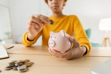 Gelecek için para yatırımı biriktiriyorum. Afrika kökenli Amerikalı bir kız pembe domuz kumbarası tutuyor ve para koyuyor. Yatırım bütçesi tasarrufu iş zenginliği emeklilik finansal para bankacılık kavramı