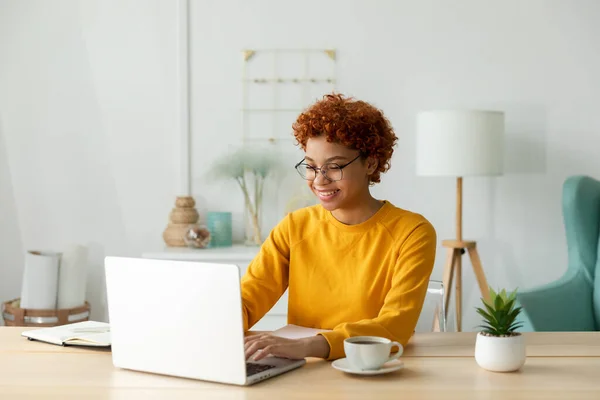 stock image African american girl using laptop at home office looking at screen typing chatting reading writing email. Young woman having virtual meeting online chat video call conference. Work learning from home
