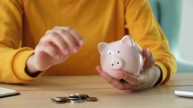 Gelecek için para yatırımı biriktiriyorum. Kadın elleri pembe kumbarayı tutuyor ve para koyuyor. Yatırım bütçesi tasarrufu iş zenginliği emeklilik finansal para bankacılık kavramı