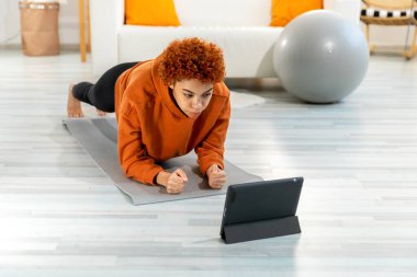 Fitness Workout training. Young healthy fit african girl doing plank exercise on yoga mat on floor at home. Athletic woman in sportswear training pilates. Sport and fitness