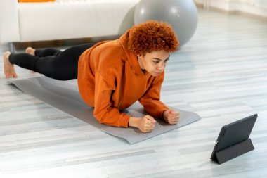Fitness Workout training. Young healthy fit african girl doing plank exercise on yoga mat on floor at home. Athletic woman in sportswear training pilates. Sport and fitness