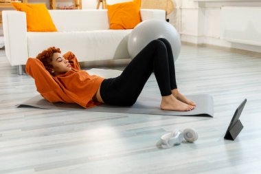 Fitness Workout training. Young healthy fit african girl doing bicycle crunch abs exercise on yoga mat on floor at home. Athletic woman in sportswear is pumping abdominals. Sport and fitness