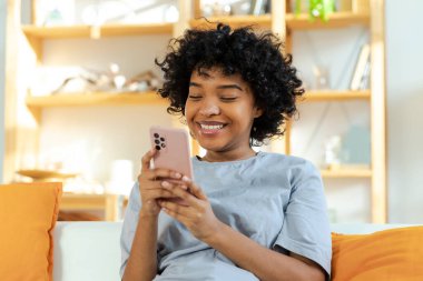 Akıllı telefon tutan Afrikalı bir kız. Evde parşömen sayfasına dokunuyor. Sosyal medya uygulamaları kullanarak internette cep telefonu sörfü yapan bir kadın. İnternet üzerinden haber alışverişi cep telefonu bağımlılığı