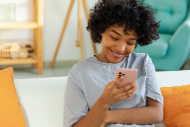 Akıllı telefon tutan Afrikalı bir kız. Evde parşömen sayfasına dokunuyor. Sosyal medya uygulamaları kullanarak internette cep telefonu sörfü yapan bir kadın. İnternet üzerinden haber alışverişi cep telefonu bağımlılığı
