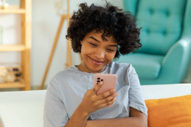 Akıllı telefon tutan Afrikalı bir kız. Evde parşömen sayfasına dokunuyor. Sosyal medya uygulamaları kullanarak internette cep telefonu sörfü yapan bir kadın. İnternet üzerinden haber alışverişi cep telefonu bağımlılığı