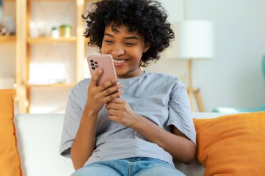 Akıllı telefon tutan Afrikalı bir kız. Evde parşömen sayfasına dokunuyor. Sosyal medya uygulamaları kullanarak internette cep telefonu sörfü yapan bir kadın. İnternet üzerinden haber alışverişi cep telefonu bağımlılığı