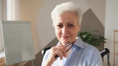 İş yerinde kendine güveni tam orta yaşlı Avrupalı bir kadının portresi. Modern ofisteki yaşlı, şık, 60 'lı yaşlarda, beyaz saçlı, bayan iş kadını. Patron öğretmen profesyonel işçi.