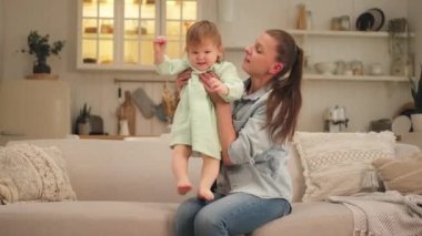 Evde mutlu bir aile. Anne kucağında küçük bir kız çocuğu taşıyor. Anne ve küçük kız evde birlikte eğleniyorlar. Anne bebeğe sevgiyle sarılır. Genç anne çocuk oturma odasında dinleniyor.