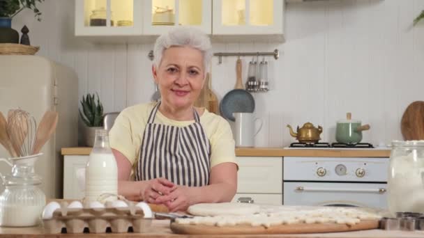 快乐的老年妇女在厨房做饭 老态龙钟的白发苍苍的老太太揉揉面团饼干 老奶奶做自制的食物 家庭主妇家务劳动概念 — 图库视频影像
