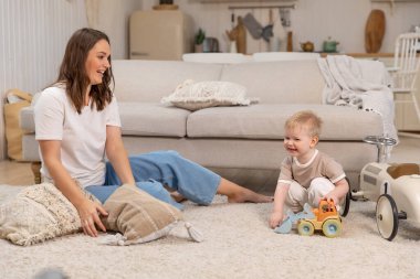 Evde mutlu bir aile. Anne ve bebek evde oyuncaklarla oynuyor. Küçük çocuk ve bebek bakıcısı birlikte eğleniyorlar. Genç kadın, anne, çocuk oturma odasında dinleniyor.