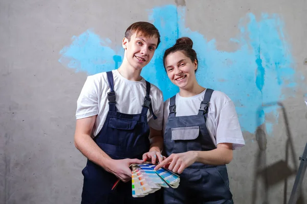 stock image House decoration DIY renovation concept. Happy couple in empty room of new home planning design. Husband and wife holding swatch palette choosing colors for painting wall in new house