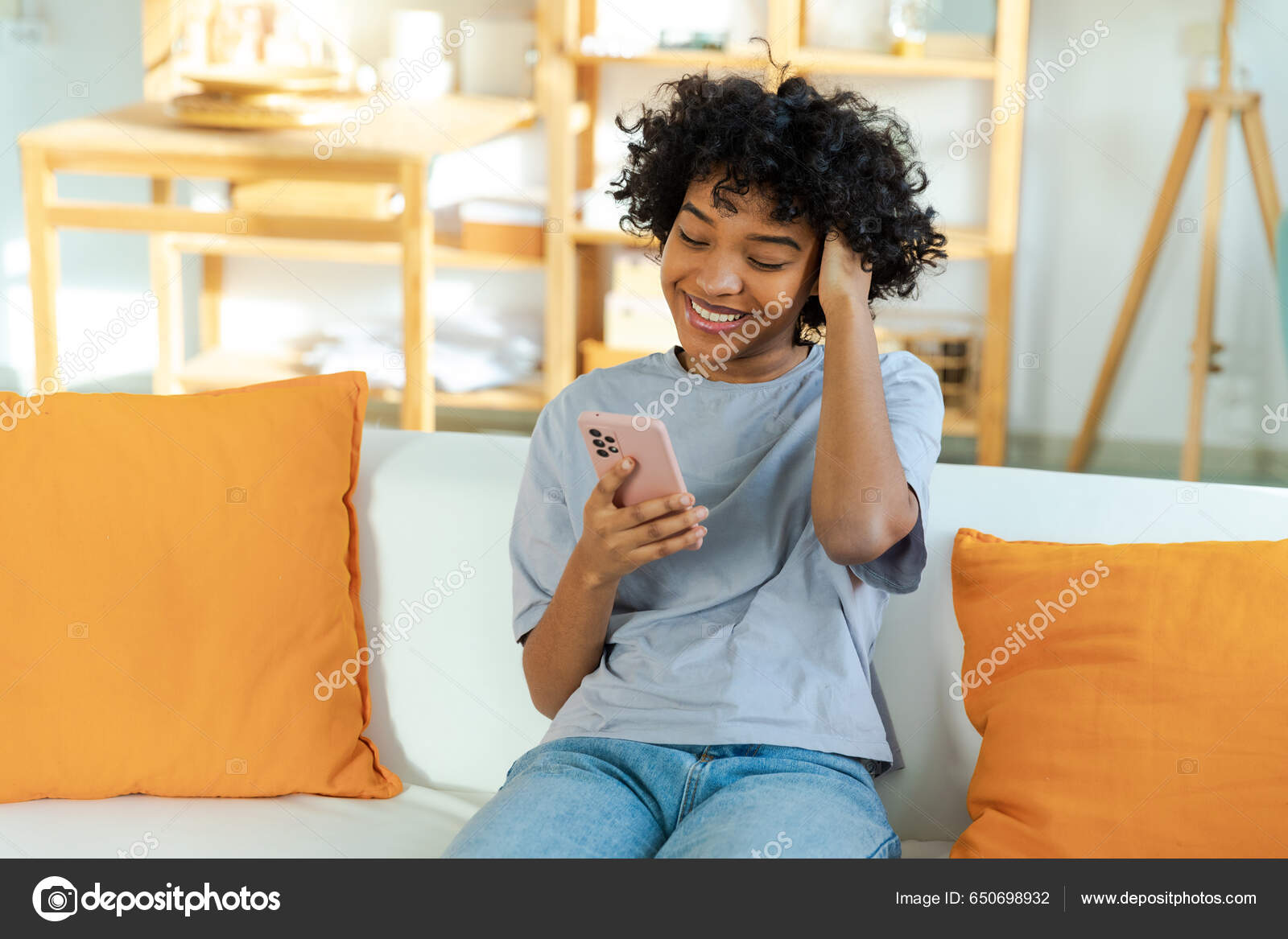 Cheerful Young African Woman Holding A Pillow And Sitting On The