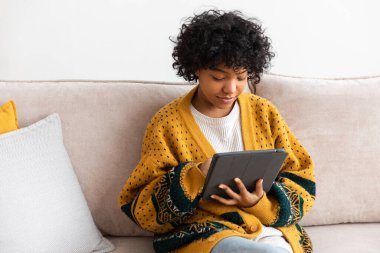 African american girl holding digital tablet touch screen typing scroll page at home. Woman with mobile tech device surfing internet using social media apps playing game. Study work shopping online