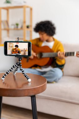 Blogger gitaristi. Mutlu Afro-Amerikan kız blogcu gitar çalıp şarkı söyleyen vlog 'cu. Sosyal medya etkisinde olan kadın stüdyoda kayıt yapıyor. Müzik içeriği oluşturucu yayını