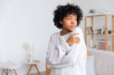 Beautiful african american girl with afro hairstyle at home indoor. Young african woman with curly hair in living room. Beauty ethnic people, domestic life concept