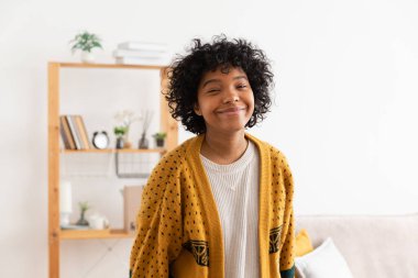 Afro saç stili evde gülümseyen güzel Afro-Amerikalı kız. Kıvırcık saçlı genç Afrikalı kadın oturma odasında gülüyor. Özgürlük mutluluğu tasasız mutlu insanlar konsepti