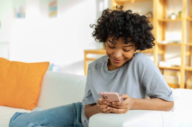 Akıllı telefon tutan Afrikalı bir kız. Evde parşömen sayfasına dokunuyor. Sosyal medya uygulamaları kullanarak internette cep telefonu sörfü yapan bir kadın. İnternet üzerinden haber alışverişi cep telefonu bağımlılığı