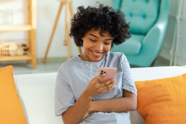 Akıllı telefon tutan Afrikalı bir kız. Evde parşömen sayfasına dokunuyor. Sosyal medya uygulamaları kullanarak internette cep telefonu sörfü yapan bir kadın. İnternet üzerinden haber alışverişi cep telefonu bağımlılığı