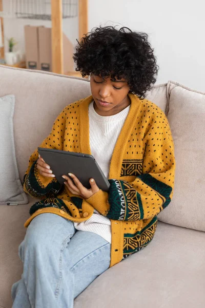 stock image African american girl holding digital tablet touch screen typing scroll page at home. Woman with mobile tech device surfing internet using social media apps playing game. Study work shopping online