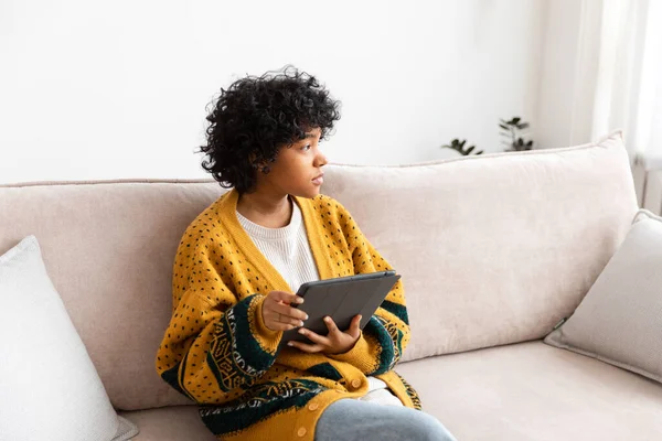 stock image African american girl holding digital tablet touch screen typing scroll page at home. Woman with mobile tech device surfing internet using social media apps playing game. Study work shopping online