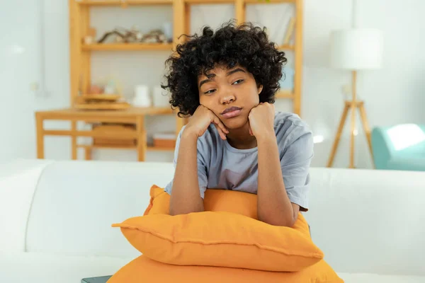 stock image African american sad thoughtful pensive unmotivated girl sitting on sofa at home indoor. Young african woman ponder look tired after long day. Girl feels depressed offended lonely upset heartbreak