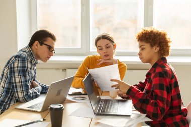 Takım çalışması beyin fırtınası. Çeşitli meslektaşlar birlikte çalışarak mali istatistikleri tartışırlar. Bir grup mutlu modern insan yaratıcı ofiste oturmuş iş tartışıyorlar. Genç profesyonel takım