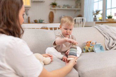 Evde mutlu bir aile. Anne ve bebek evdeki kanepede oyuncaklarla oynuyor. Küçük çocuk ve bebek bakıcısı birlikte eğleniyorlar. Genç kadın, anne, çocuk oturma odasında dinleniyor.