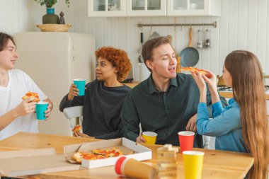 Ev partisi. Arkadaşlar birlikte vakit geçirip gülerek ve evde iletişim kurarak eğleniyorlar. Bira ya da limonata içerek pizza yiyen mutlu bir grup. Karışık yarış genç dostları, en iyi arkadaşlar hafta sonunun tadını çıkarın.