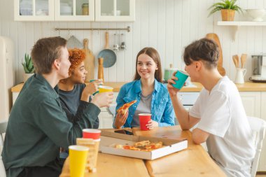 Ev partisi. Arkadaşlar birlikte vakit geçirip gülerek ve evde iletişim kurarak eğleniyorlar. Bira ya da limonata içerek pizza yiyen mutlu bir grup. Karışık yarış genç dostları, en iyi arkadaşlar hafta sonunun tadını çıkarın.
