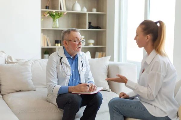 stock image Senior man doctor examining yound woman in doctor office or at home. Girl patient and doctor have consultation in hospital room. Medicine healthcare medical checkup. Visit to doctor