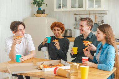 Ev partisi. Arkadaşlar birlikte vakit geçirip gülerek ve evde iletişim kurarak eğleniyorlar. Bira ya da limonata içerek pizza yiyen mutlu bir grup. Karışık yarış genç dostları, en iyi arkadaşlar hafta sonunun tadını çıkarın.