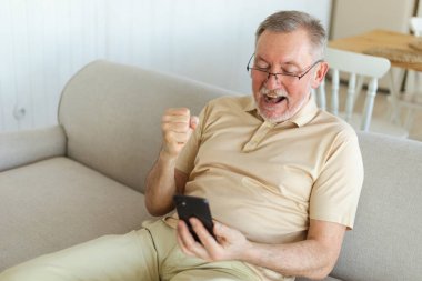 Orta yaşlı son sınıf öğrencisi, akıllı telefonuyla çok mutlu. Yaşlı, olgun büyükbaba cep telefonuna bakıyor. Harika haberler okuyor. İnternetteki ihaleyi kazanırken çok şaşırdı. Kazanan jest