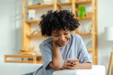 Akıllı telefon tutan Afrikalı bir kız. Evde parşömen sayfasına dokunuyor. Sosyal medya uygulamaları kullanarak internette cep telefonu sörfü yapan bir kadın. İnternet üzerinden haber alışverişi cep telefonu bağımlılığı