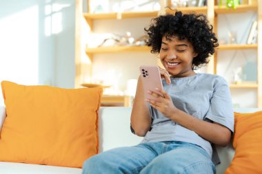 Akıllı telefon tutan Afrikalı bir kız. Evde parşömen sayfasına dokunuyor. Sosyal medya uygulamaları kullanarak internette cep telefonu sörfü yapan bir kadın. İnternet üzerinden haber alışverişi cep telefonu bağımlılığı