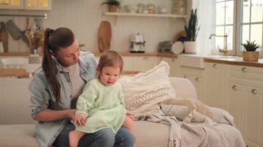 Evde mutlu bir aile. Anne ve bebek evdeki kanepede oynuyorlar. Küçük çocuk ve bebek bakıcısı birlikte eğleniyorlar. Genç kadın anne, küçük kız oturma odasında dinleniyor.