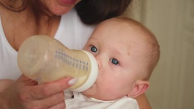 Evde mutlu bir aile. Anne kucağında küçük bir bebek, sütü şişeden besliyor. Yeni doğmuş bebek kız bebek süt içiyor. Bebeği emziren anne. Annelik mutlu çocuk