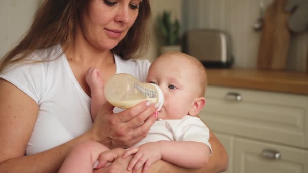 家庭で幸せな家族 母親は哺乳瓶からミルクを与える小さな赤ちゃんの幼児を保持しています 新生児の乳児は牛乳を飲んで吸う 母乳育児の母親 母親の幸せな子供 — ストック動画