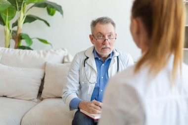 Kıdemli doktor, genç kadını muayenehanede ya da evde muayene ediyor. Kız hasta ve doktorun hastane odasında muayenesi var. Tıbbi sağlık hizmetleri sağlık kontrolü. Doktoru ziyaret et.